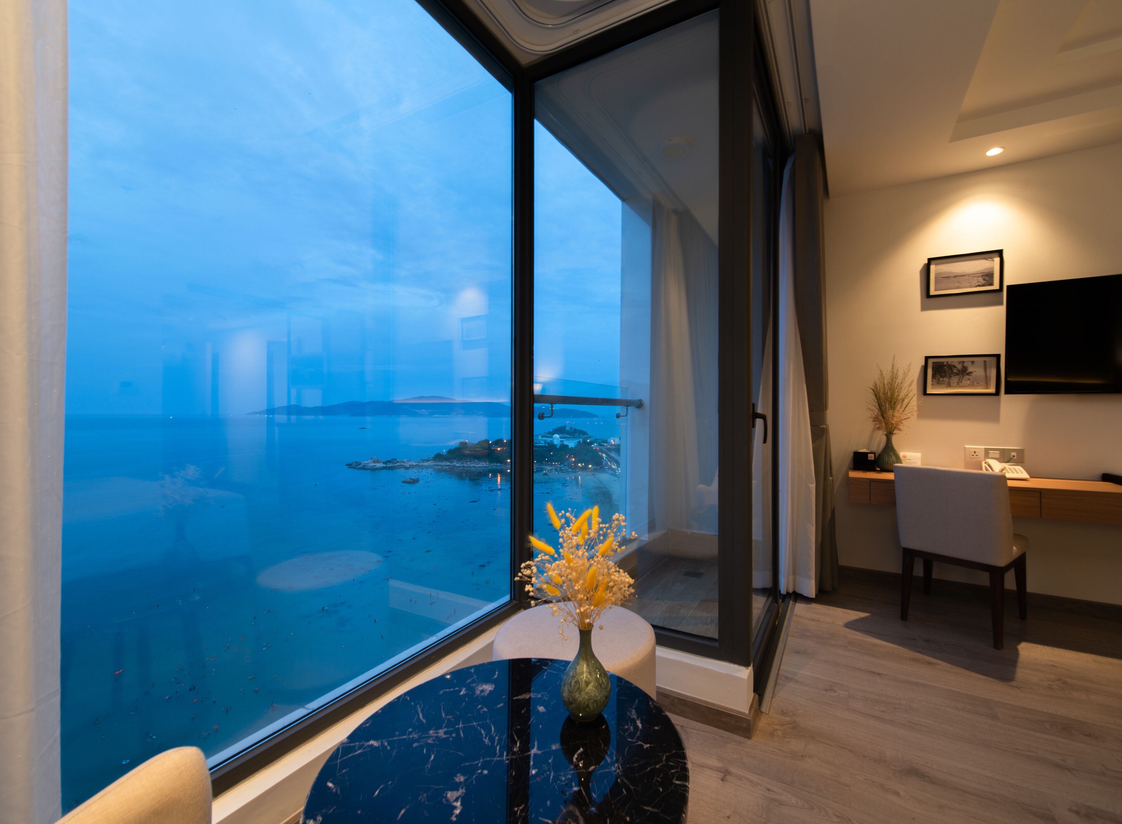 A modern room with a large glass door leading to a balcony overlooking a body of water.