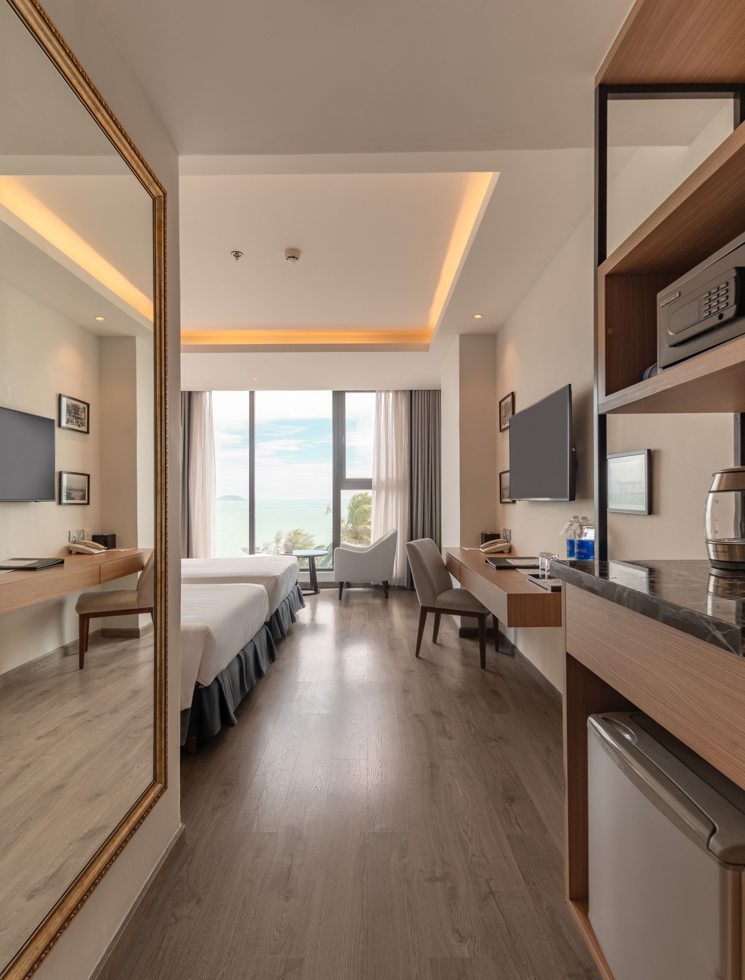 Habitació d'hotel amb llit, escriptori, cadira i un gran mirall.