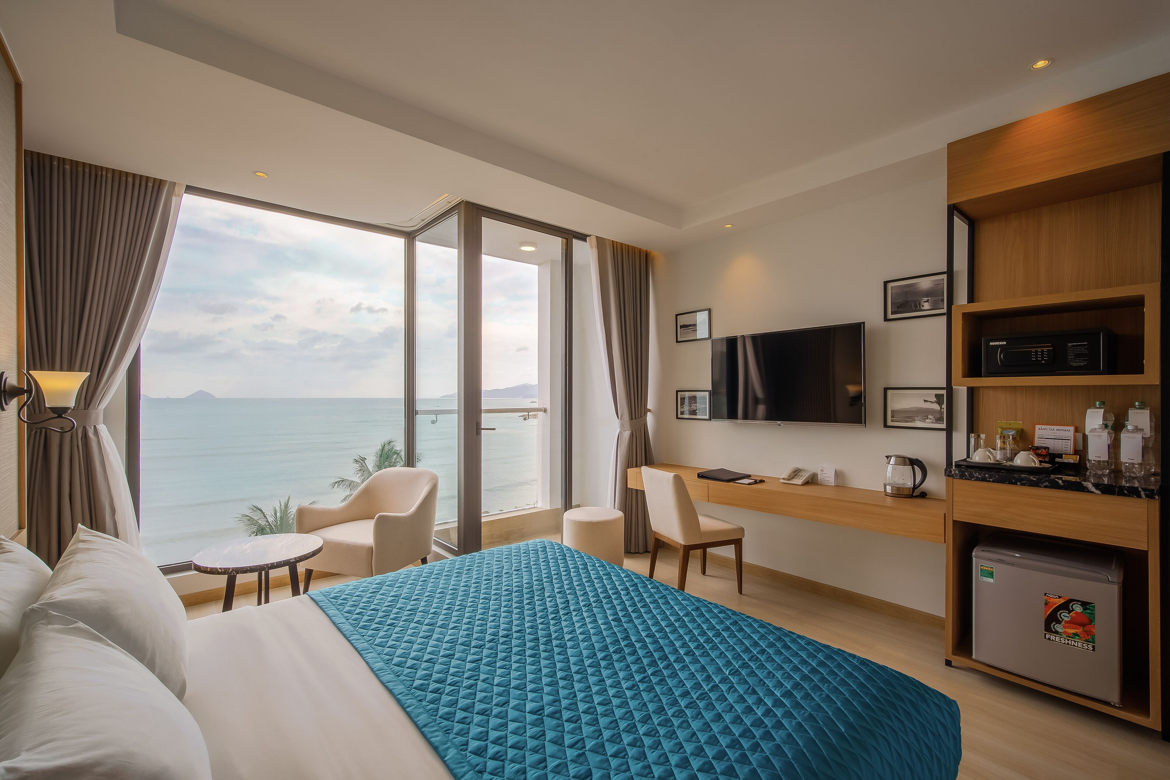 A hotel room with a bed, a desk, a TV, and a minibar.