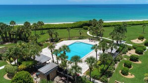 An aerial view of a resort with a swimming pool surrounded by palm trees and a view of the ocean. - Vanderbilt Gulfside on Vanderbilt Beach (Naples)