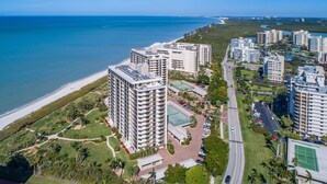 A high-rise hotel with multiple floors, a parking area, and a view of the beach and ocean. - Vanderbilt Gulfside on Vanderbilt Beach (Naples)