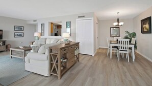 A modern living room with a sofa, coffee table, and dining area. - Vanderbilt Gulfside on Vanderbilt Beach (Naples)