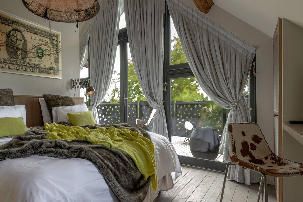 A bedroom with a large bed, a map on the wall, and a balcony with curtains.