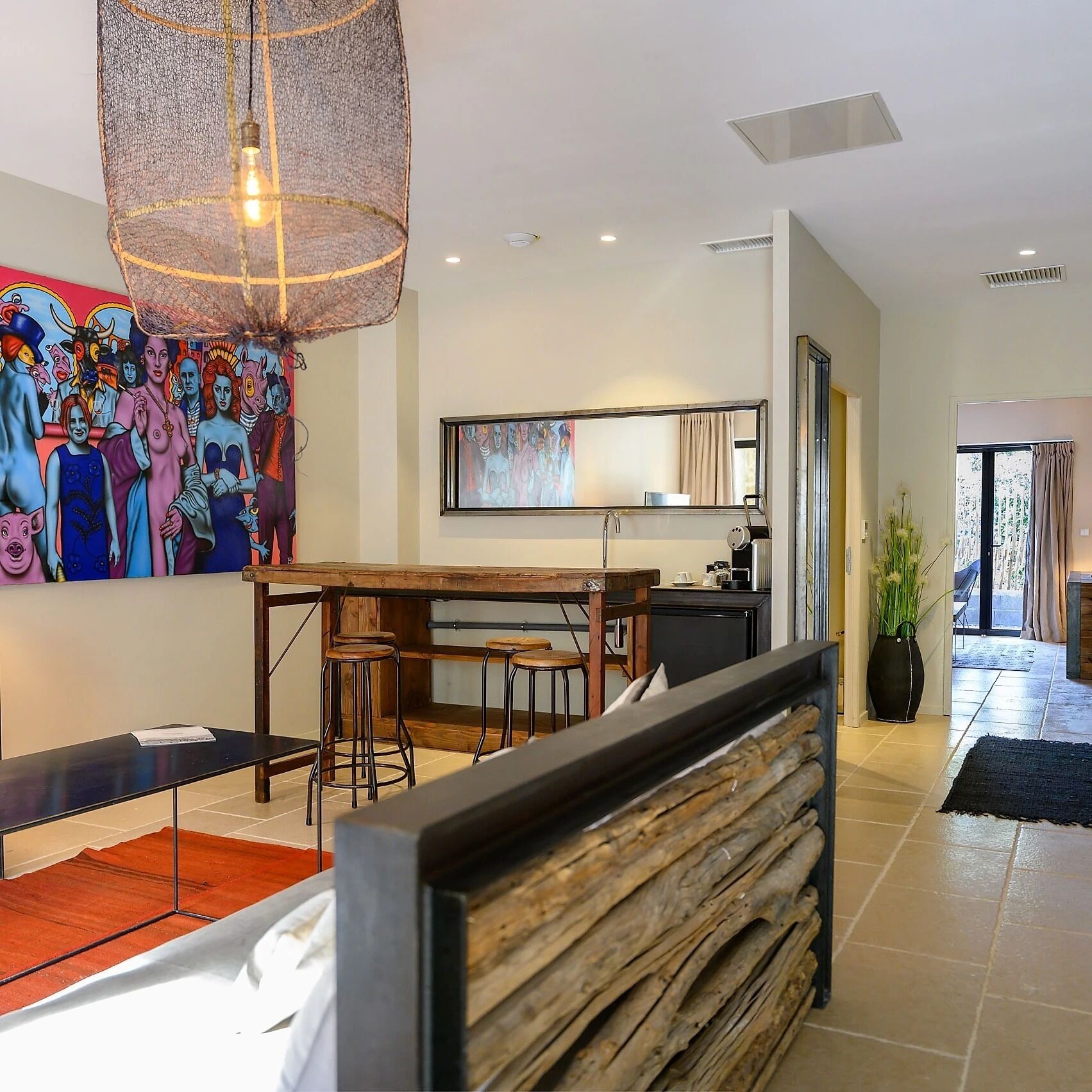 A modern kitchen with a wooden table, bar stools, and a hanging light fixture.
