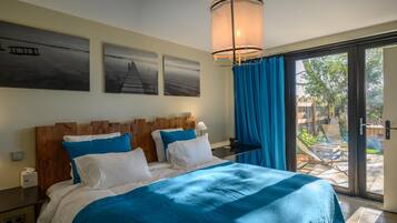 Une chambre à coucher avec un grand lit, une tête de lit en bois et une vue sur un jardin, accessible par une porte-fenêtre coulissante.