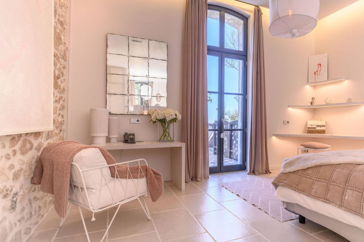 A modern bedroom with a bed, bedside table, and a large window with curtains.