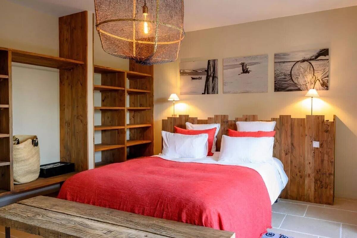 A bedroom with a wooden bed, a wooden bench, and a large window with curtains.