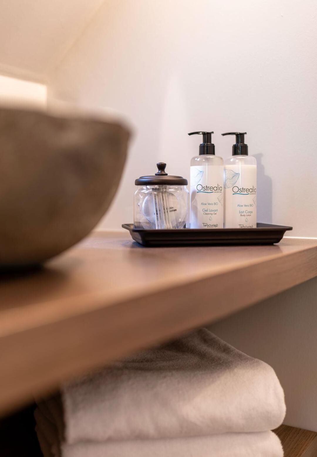A bathroom shelf with a bowl, a jar, and two bottles of skincare products.