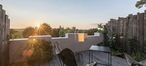 A patio with a wooden deck, a table, and chairs. - Domaine Tarbouriech (Marseillan)