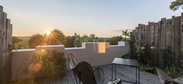 A patio with a wooden deck, a table, and chairs. - Domaine Tarbouriech (Marseillan)
