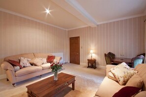 A living room with a beige sofa, a wooden coffee table, and a lamp.