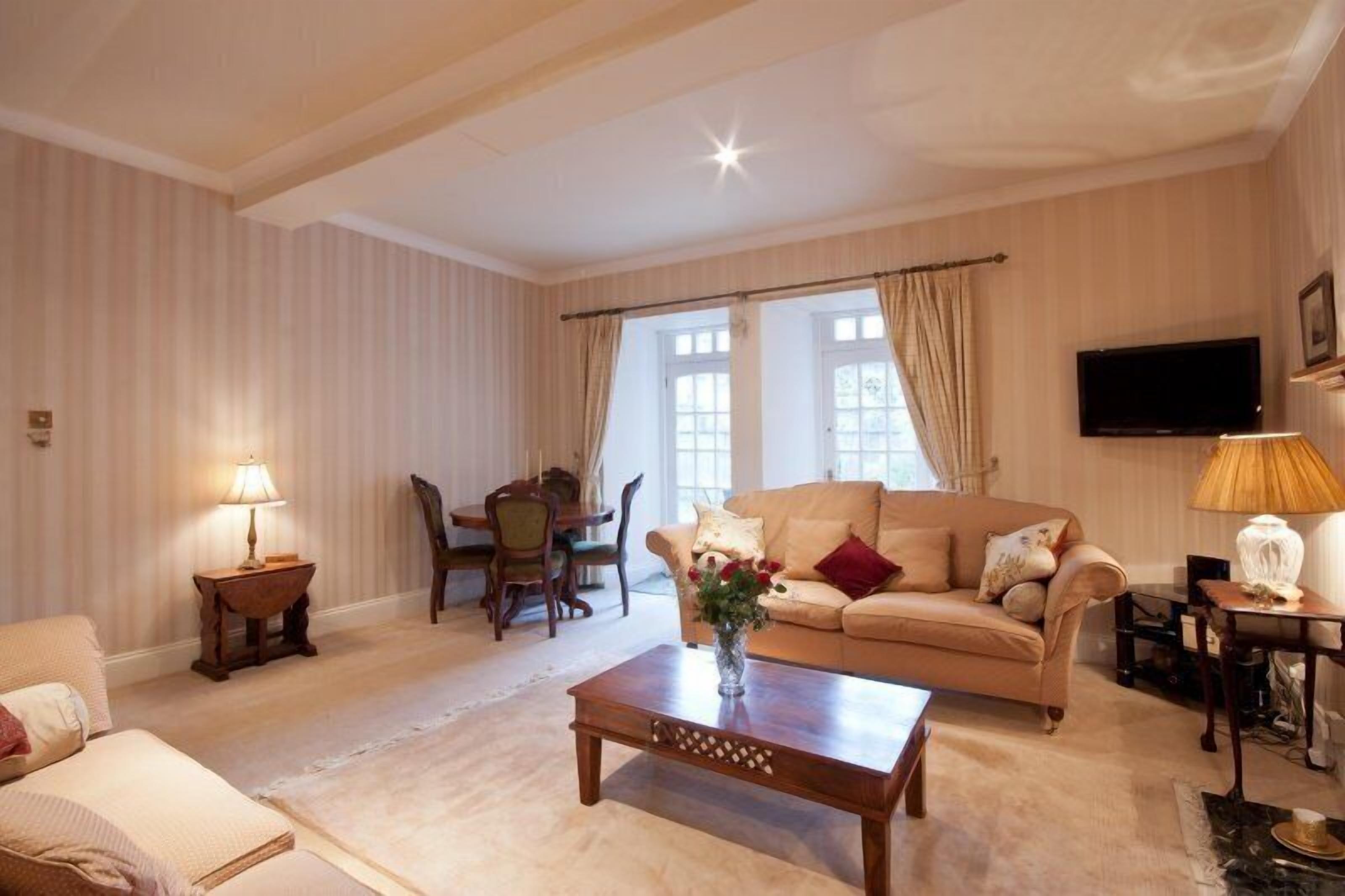 A living room with a sofa, a coffee table, a TV, and a dining area with chairs and a table.