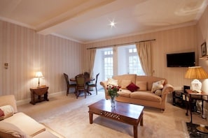 A living room with a sofa, a coffee table, a TV, and a dining area with chairs and a table.