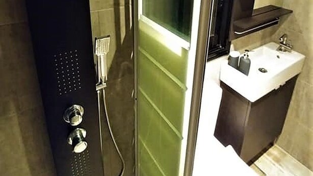 Un baño moderno con ducha envuelta en vidrio, un lavamanos y un espejo.
