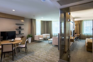 Hotellihuone, jossa on televisio, oleskelualue ja työpöytä.