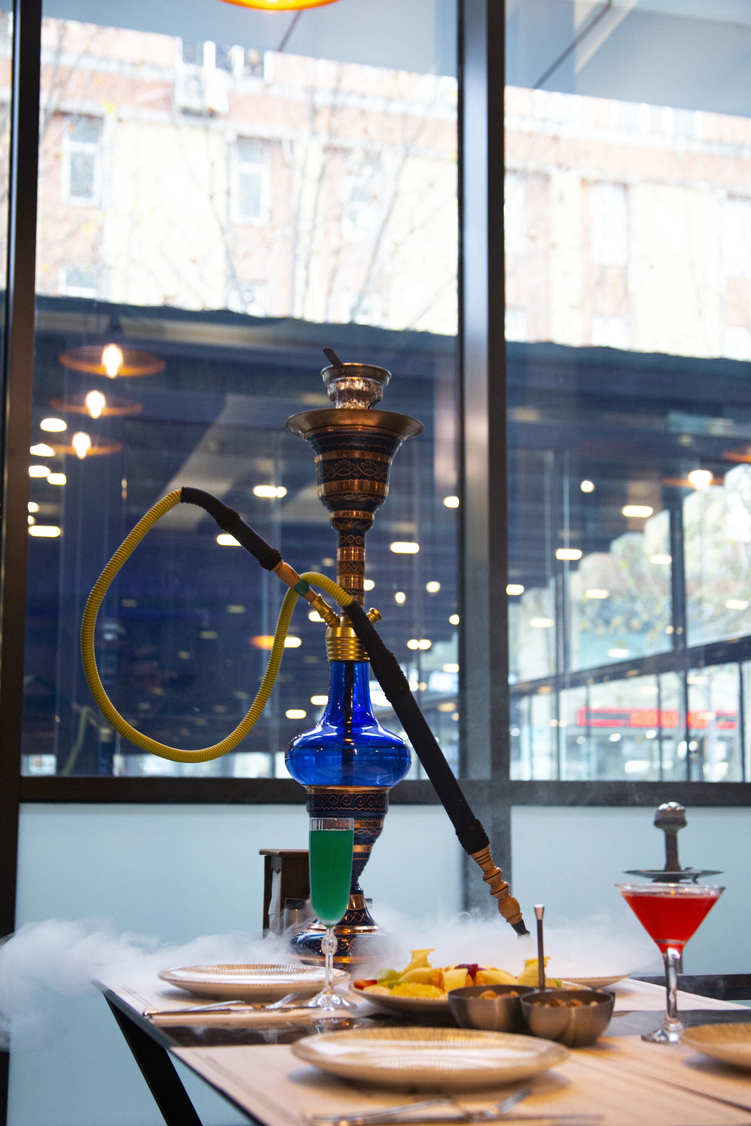 A hookah on a table with plates and a martini glass.