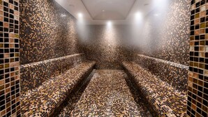 Un sauna dont les murs et les bancs sont recouverts de mosaïques.