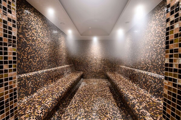 A sauna with mosaic-tiled walls and benches. - La Quinta by Wyndham Istanbul Gunesli (Istanbul)