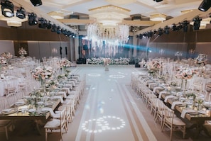 Un salón de banquetes con mesas largas, candelabros y arreglos florales.