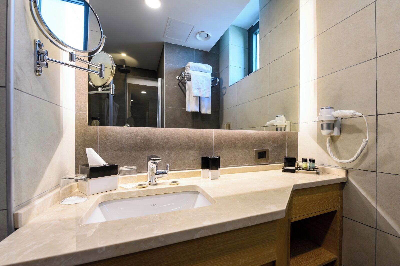 A modern bathroom with a sink, mirror, towel rack, and hairdryer.