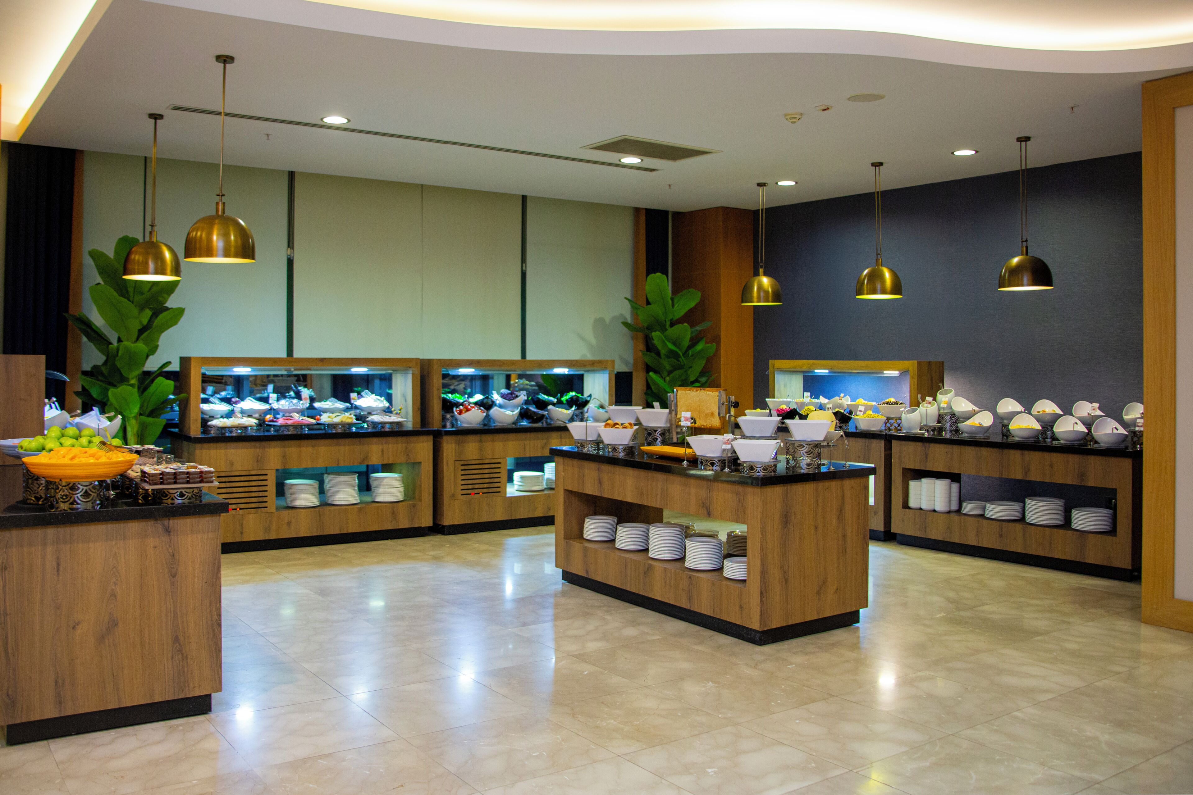 A buffet area with multiple food stations, wooden counters, and hanging pendant lights.