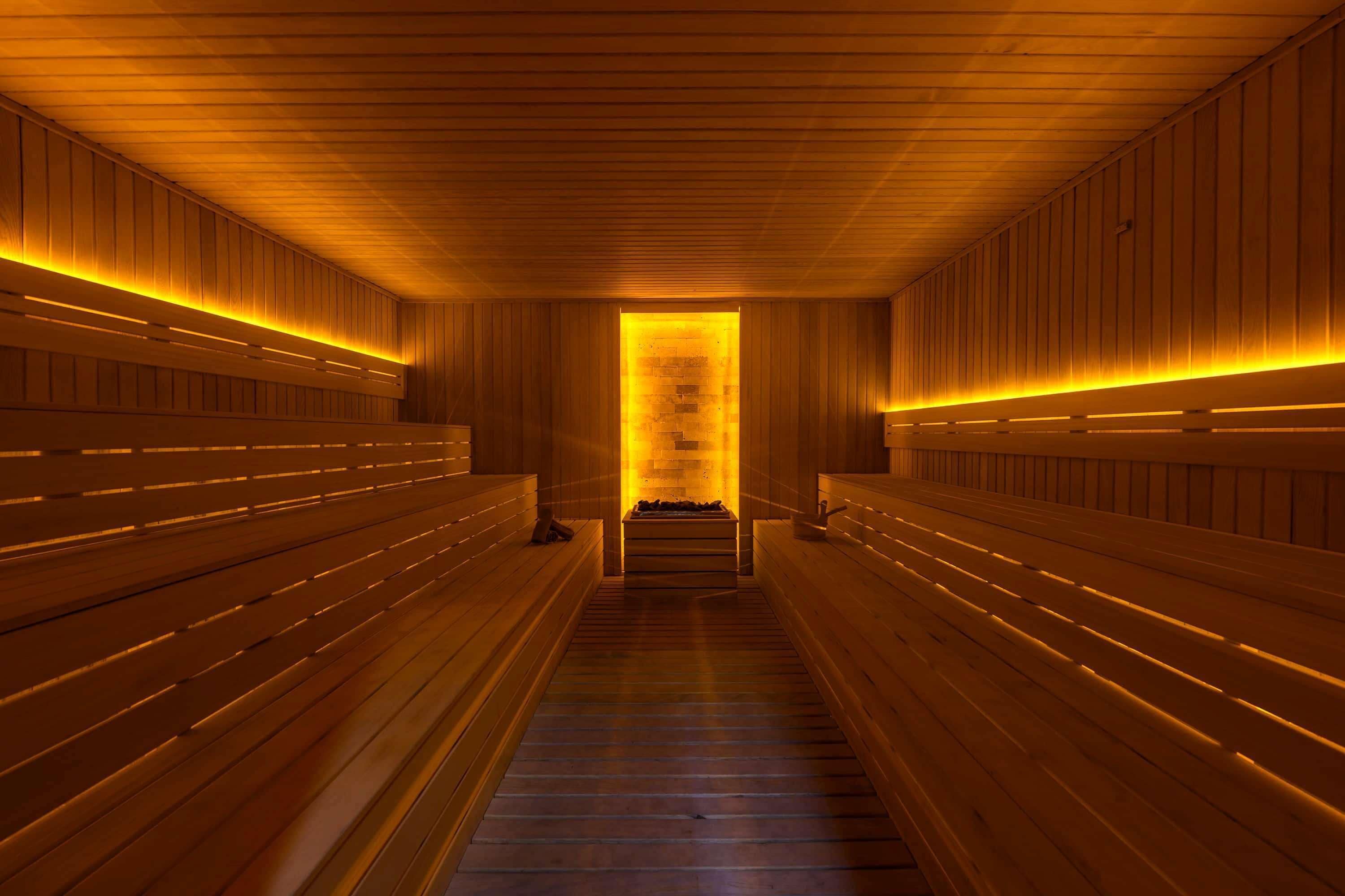 Una sauna con bancos de madera y un banco central con fuente de calor.