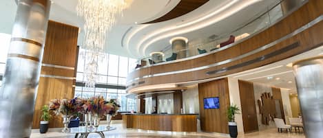Un moderno vestíbulo de hotel con una recepción, una araña y una planta grande.