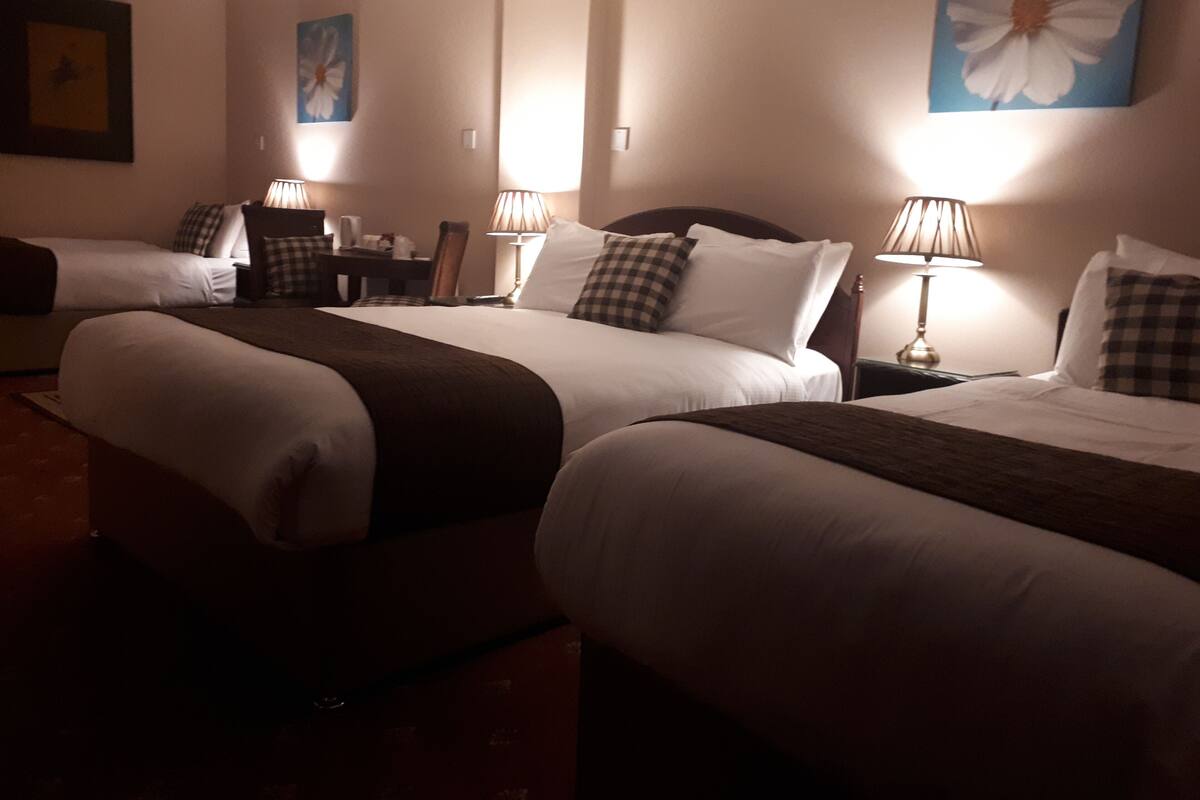 A hotel room with two beds, a desk, and a chair.