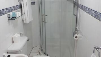 A small, modern bathroom with a glass-enclosed shower, a toilet, and a sink.