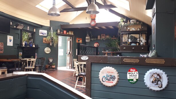 A cozy bar area with wooden furniture, vintage decor, and a green wall with various signs and memorabilia. - Jim McGee's (Wexford)