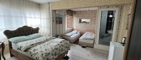 A bedroom with a large bed, two smaller beds, a wardrobe, a mirror, and a bathroom with a toilet and sink.