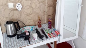 Una kitchenette pequeña con cafetera, hervidor y varios utensilios de cocina sobre una mesa.