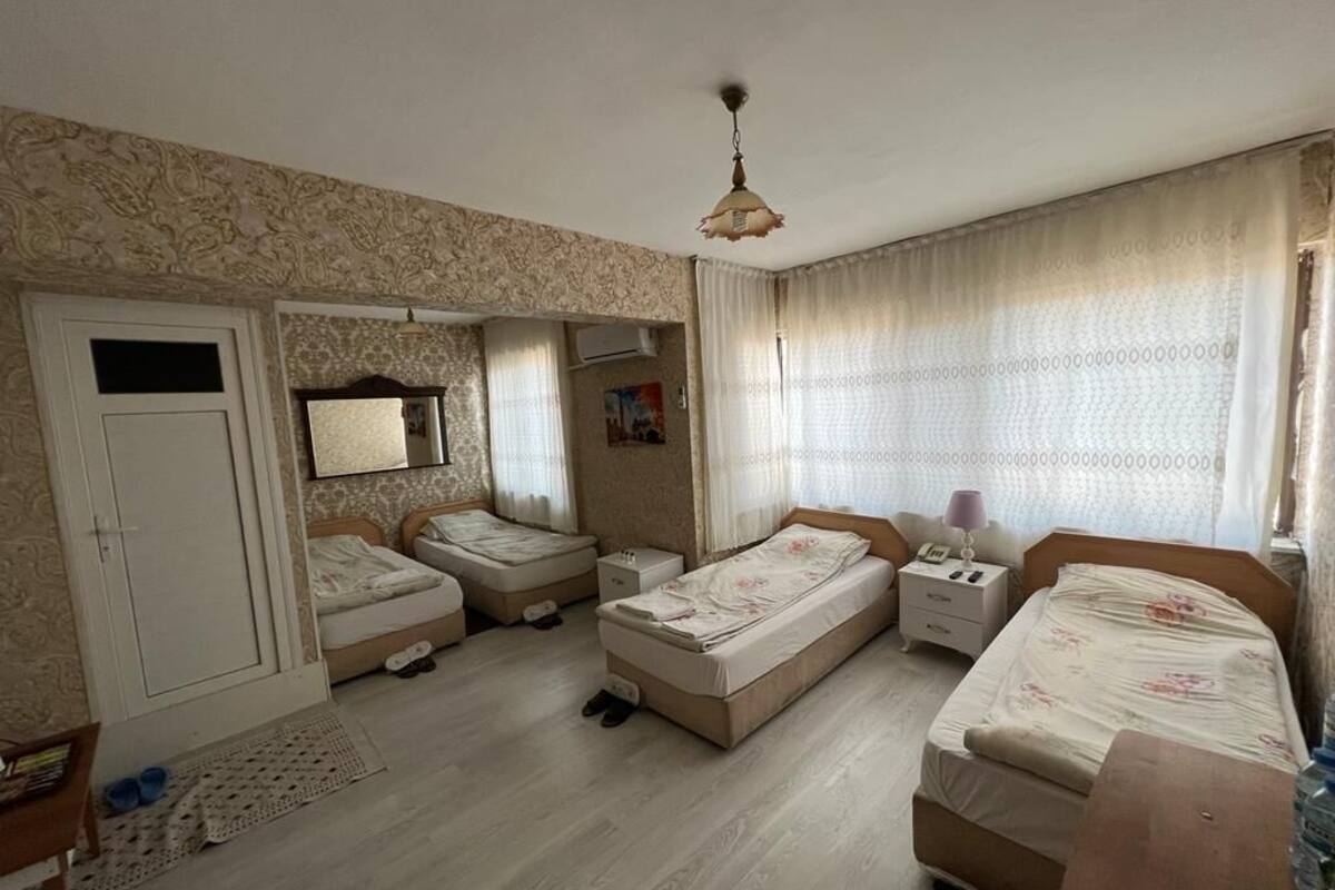 A bedroom with two beds, a wardrobe, a desk, and a mirror.