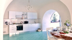 Una cuina amb armaris blancs, una cuina i una zona de dinar amb una taula preparada per a dues persones.