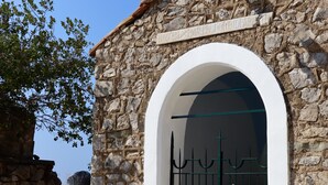 Un edifici de pedra amb una torre campanar, una entrada apuntada i una reixa metàl·lica.