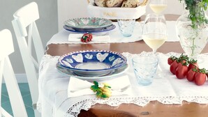 Taula de menjador preparada amb plats, gots i un ram de flors.