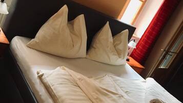 A bed with white bedding and pillows, a dark headboard, and a painting on the wall.