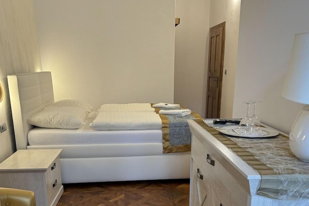 A bedroom with a bed, bedside tables, a nightstand, a dresser, and a wooden floor.