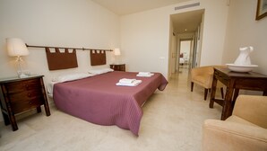 A hotel room with a bed, two bedside tables, a chair, a desk, and a lamp.