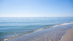 A beach with clear blue water and a sandy shore.