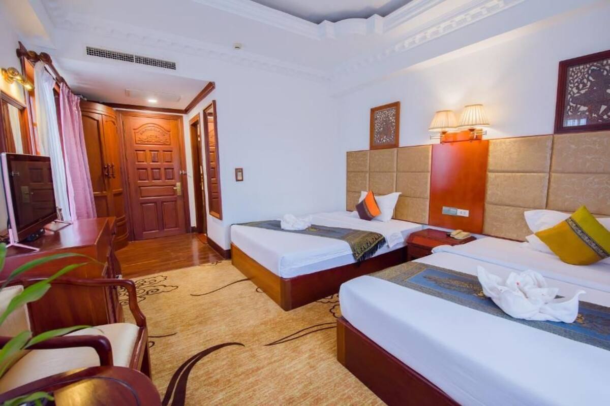Una habitación de hotel con dos camas, televisión, escritorio y una silla.