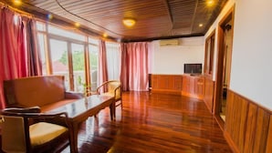 Una habitación amplia con suelo de madera, un sofá, una mesa de comedor y un televisor.