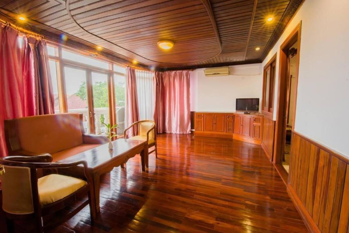 Una habitación amplia con suelo de madera, un sofá, una mesa de comedor y un televisor.