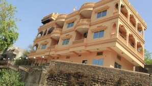 Un edificio de varios pisos con balcones y ventanas, que presenta una pared de piedra en primer plano.