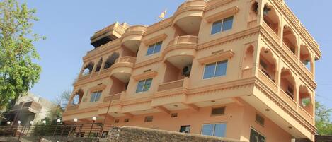 Un edificio de varios pisos con balcones y ventanas, que presenta una pared de piedra en primer plano.