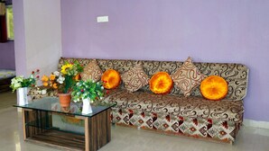 Un sofá con cojines estampados, una mesa de centro de vidrio y plantas en macetas.