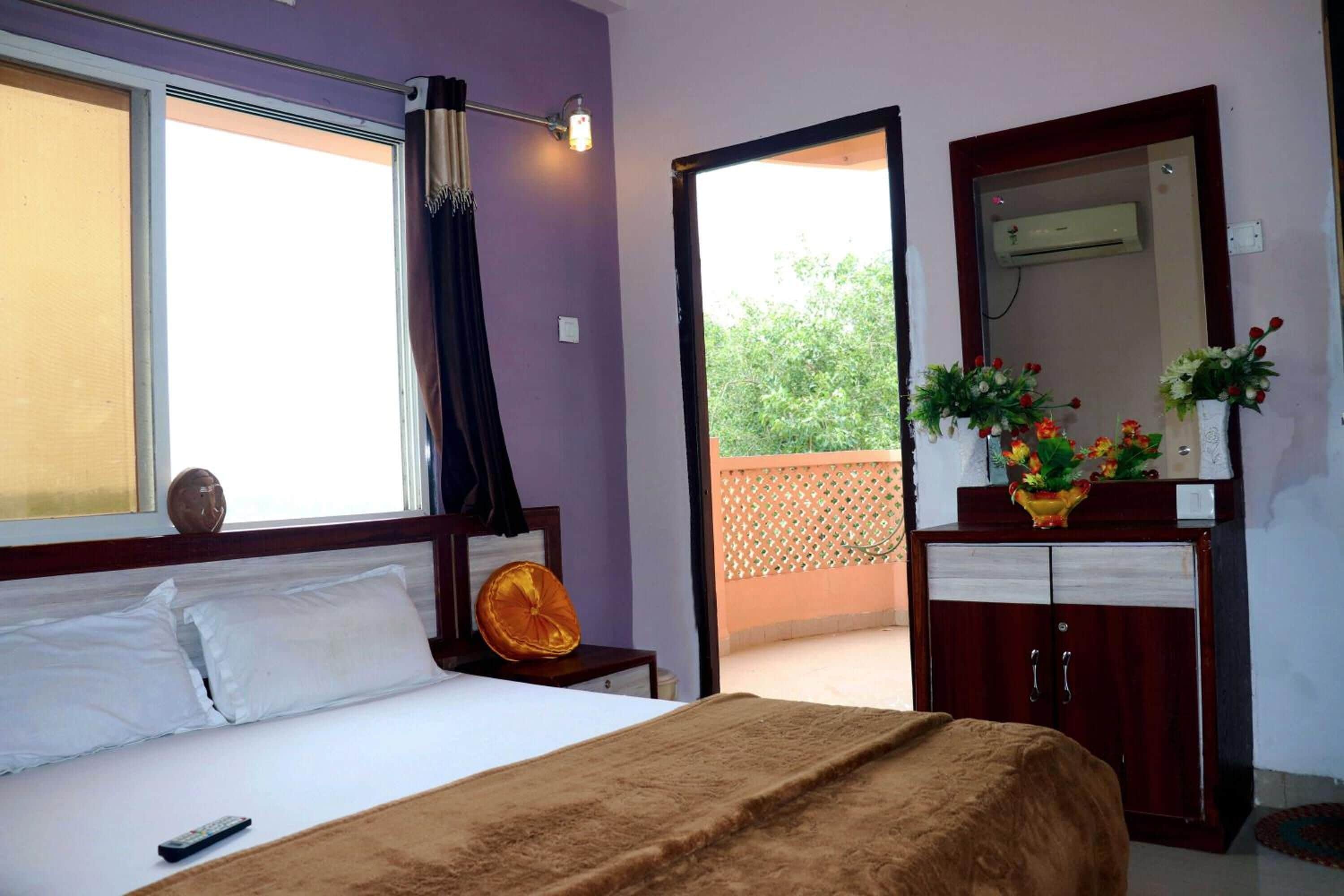 A bedroom with a bed, a nightstand, a dresser, a mirror, and a window with curtains.