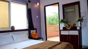 A bedroom with a bed, a nightstand, a dresser, a mirror, and a window with curtains.