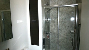 Une salle de bain moderne avec une douche à parois de verre, des toilettes blanches et un meuble-lavabo.