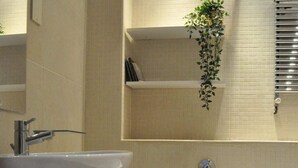 Een kleine badkamer met een wit wastafel, toilet en een klein plankje met een plant.
